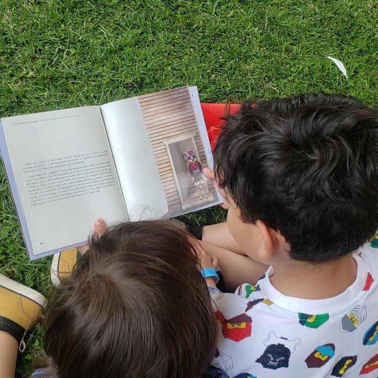 dos niños leyendo un libro sobre el pasto