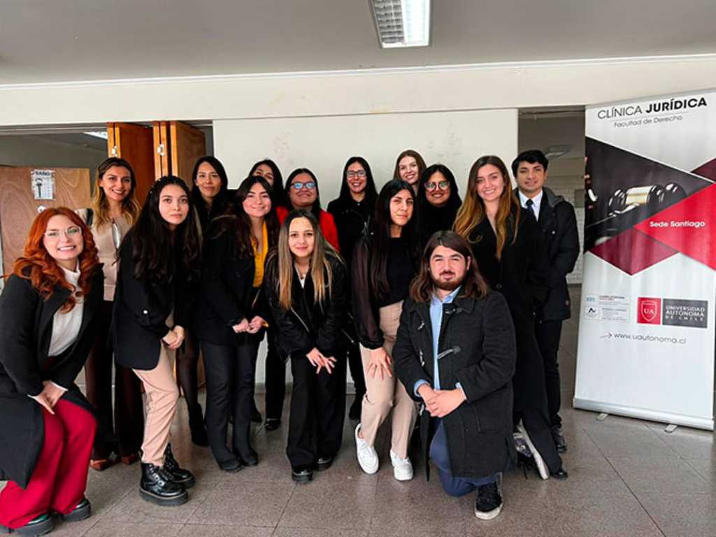 Estudiantes de Derecho junto a un cartel de la Clínica Jurídica