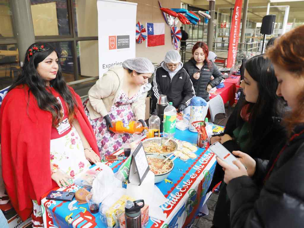 Personas visitando un stand con comida típica chilena