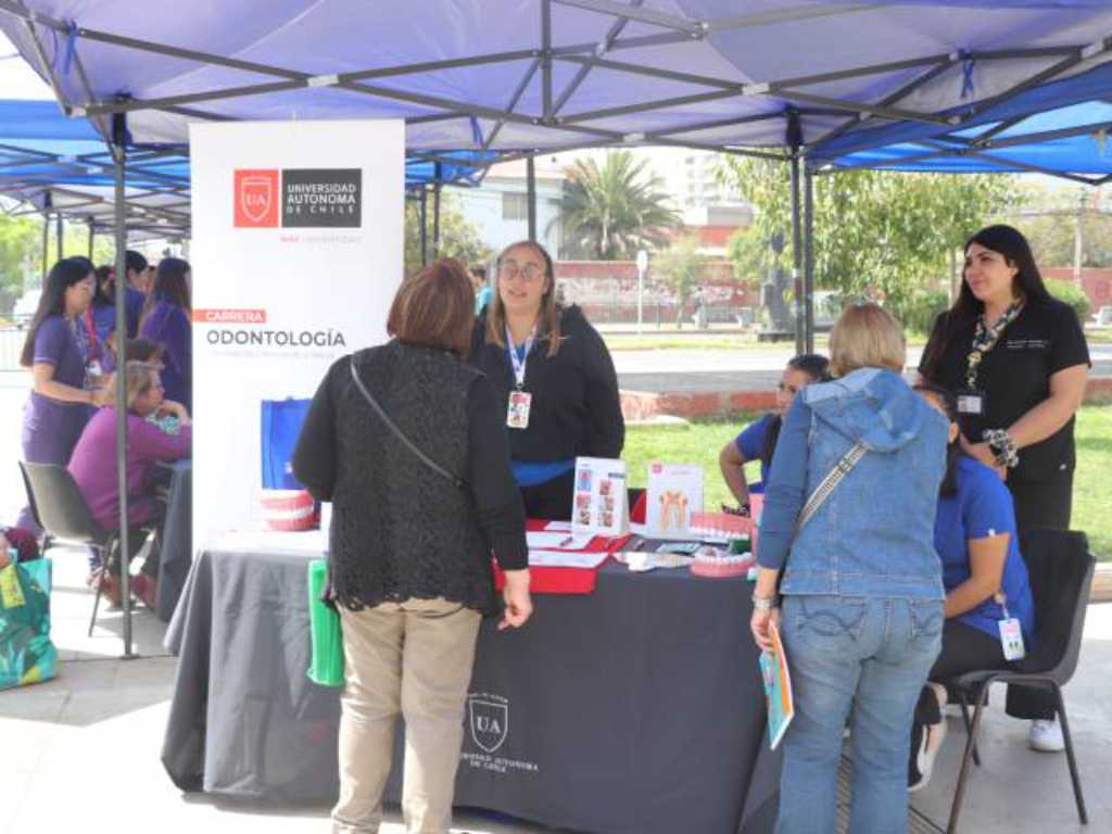 Estudiantes de odontología recibiendo a vecinas de San Miguel en su stand en la feria