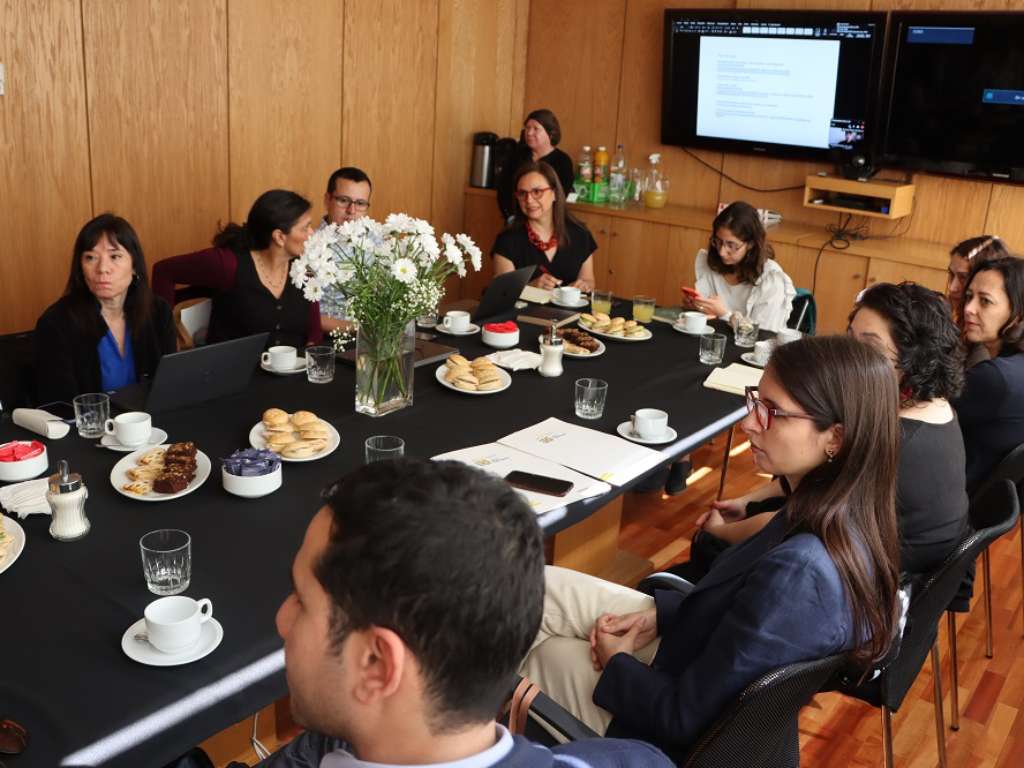 Ala derecha de la mesa con participantes escuchando la intervención de otra persona