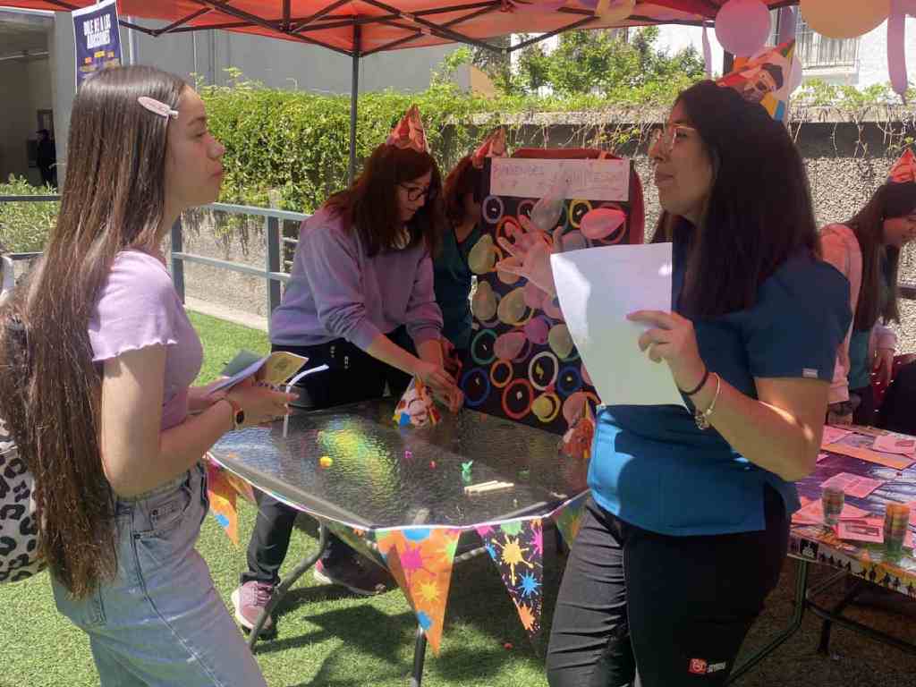 Estudiante de Terapia Ocupacional hablando con otra estudiante en la feria