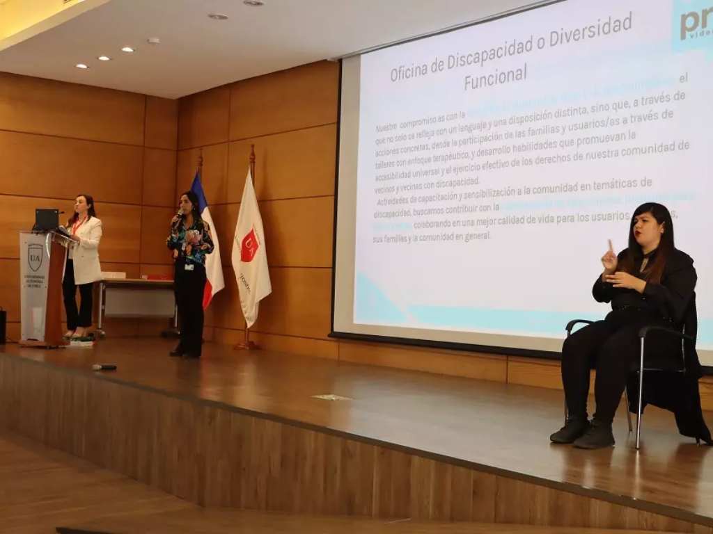Expositoras hablando en el podio acompañadas de una intérprete de lengua de señas